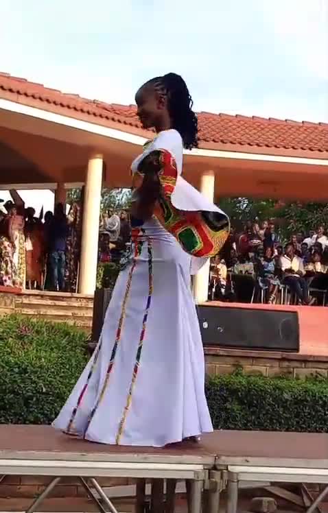 Leah Akoth Ochieng on the catwalk at Miss Culture Eldoret 2023/24, wearing a white gown with Kente panels.